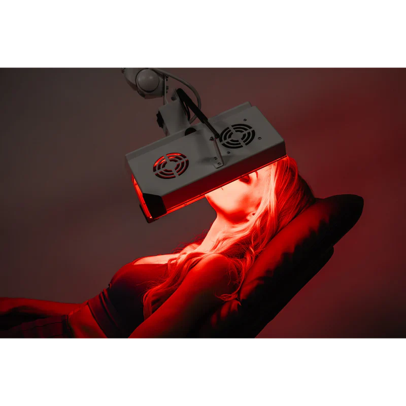 Product image prompt: Body Balance System ApolloGLOW red light therapy panel in a luxurious wellness room—tall modern LED panel emitting a soft red glow, positioned near a yoga mat and minimal furniture; clean lines, premium materials, no brand clutter; focus on device and radiant light; diffused flattering ambient lighting, film-inspired low contrast, ultra-realistic editorial product photography.